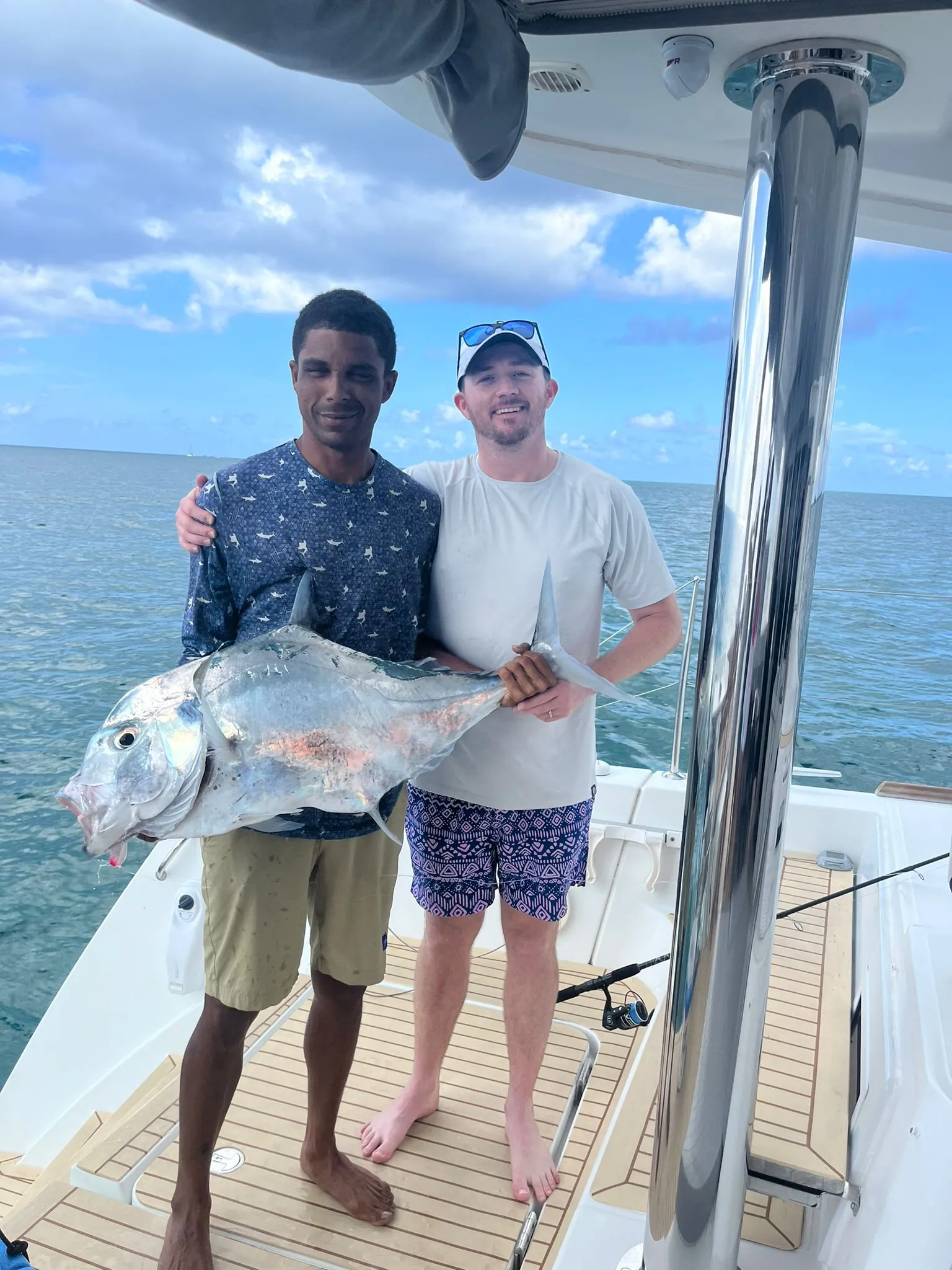 Crew member and guest with an African pompano on Bamboozled&rsquo;s aft deck