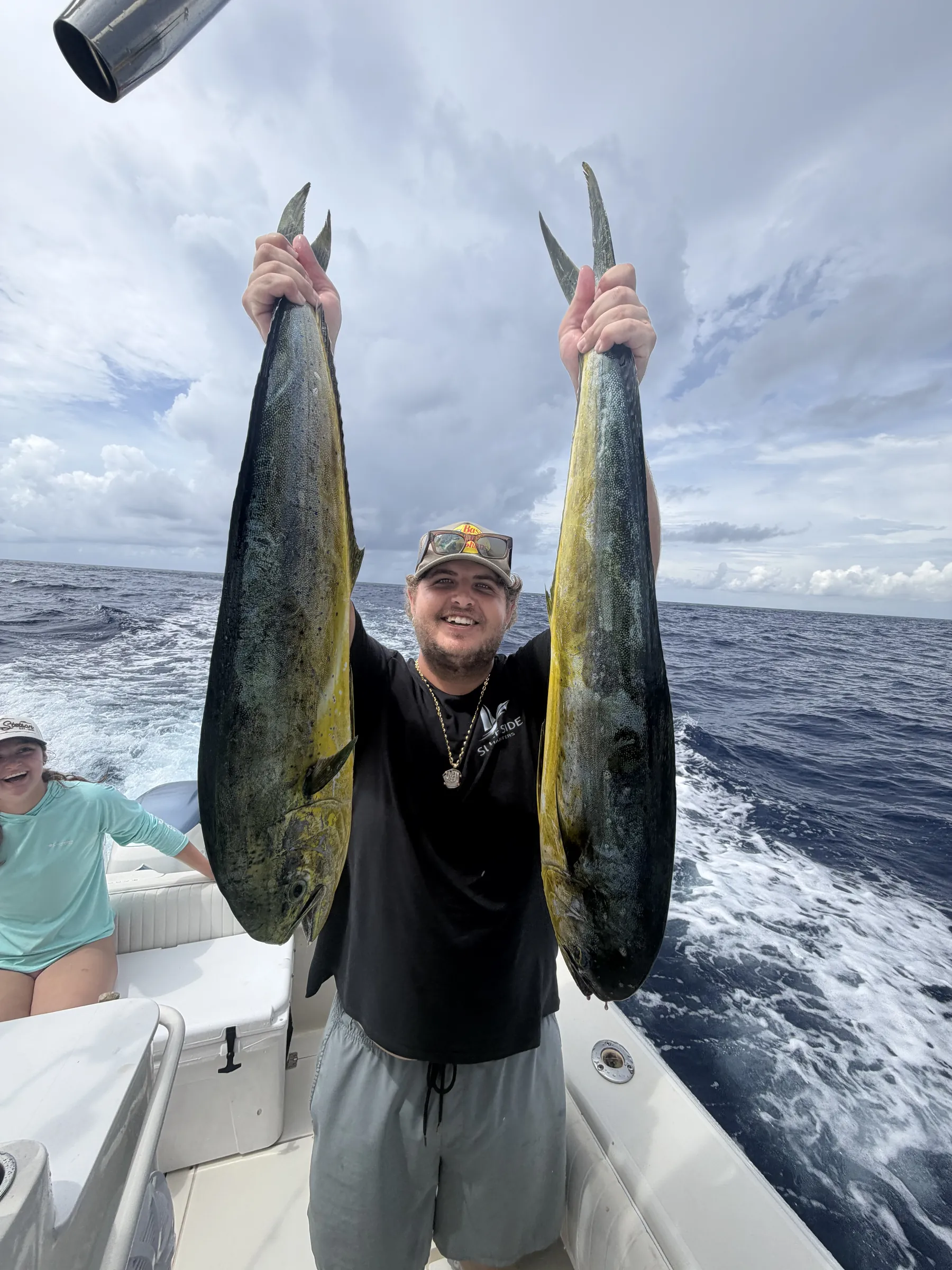 Angler holding two mahi-mahi caught deep-sea fishing