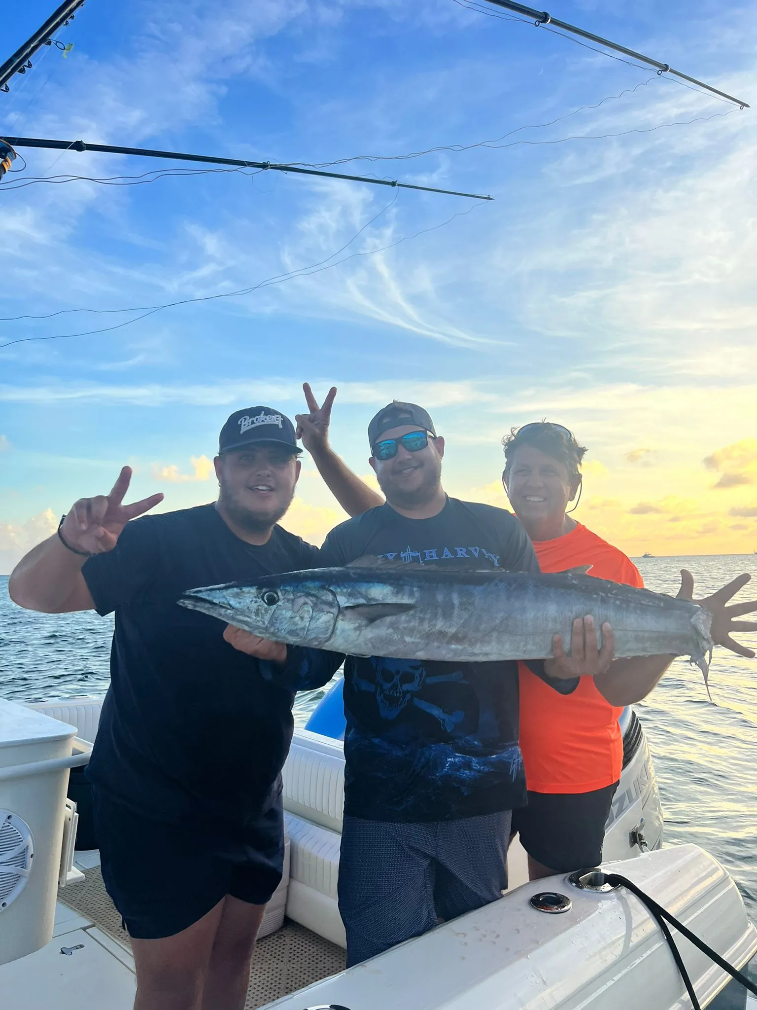 Guests with a wahoo caught on a full-day charter at sunset